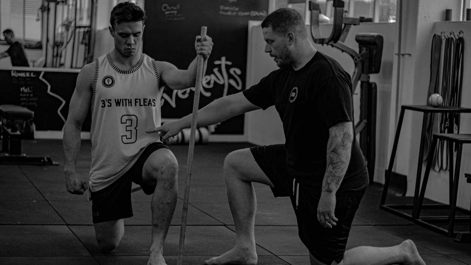 A trainer watching how a client moves and pointing out positioning.